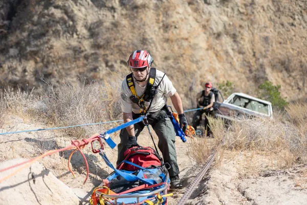A rescuer rigging a litter on a steep embankment