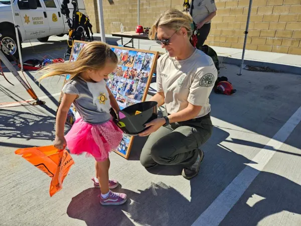 A member showing a helmet to a child at an event booth