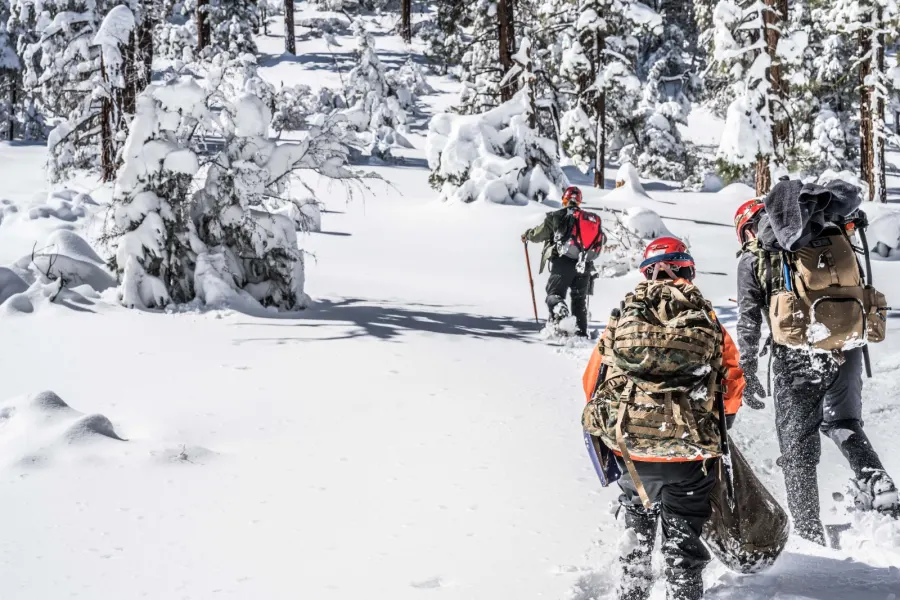 Team members hiking through deep snow carrying packs